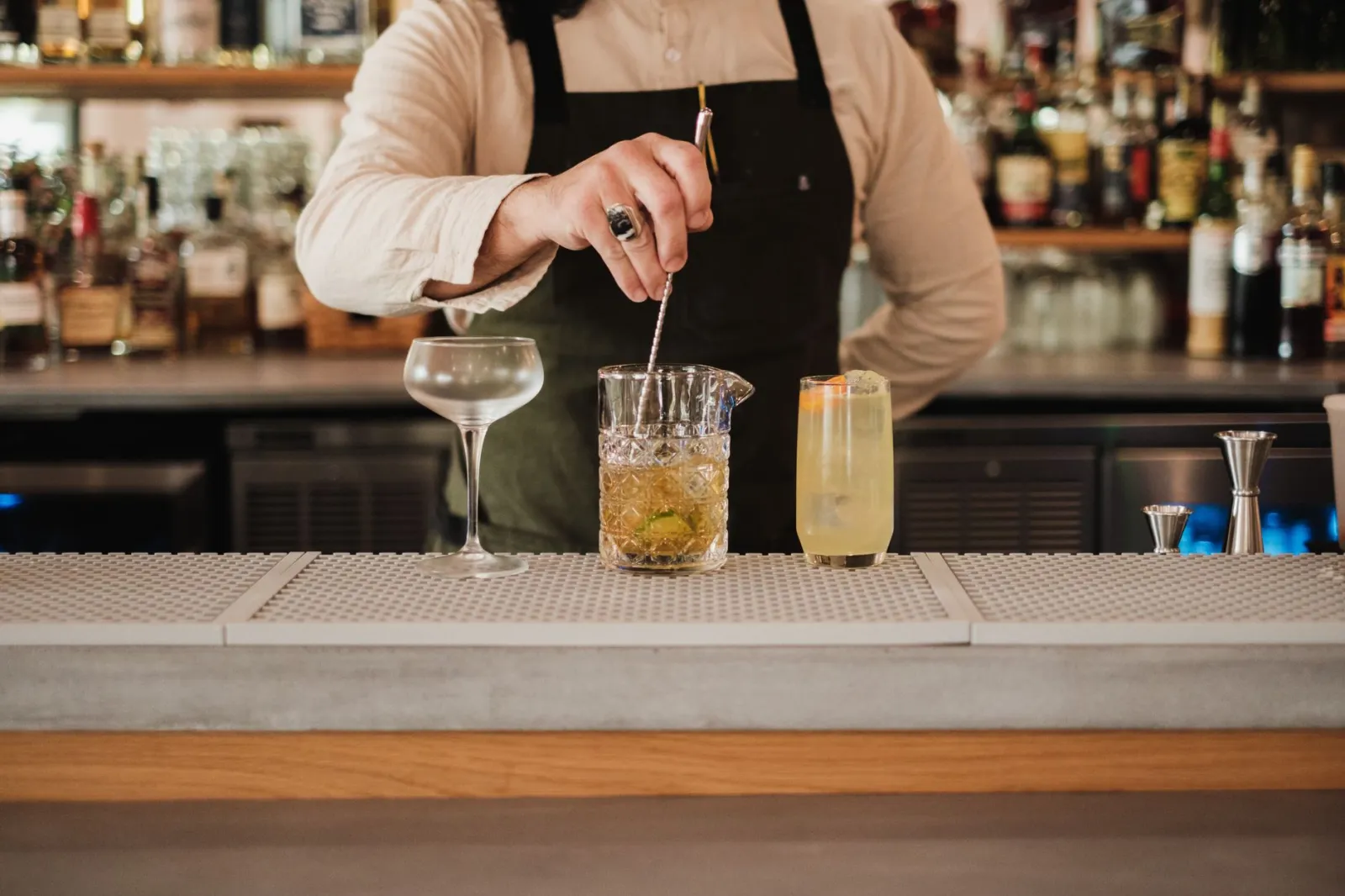 Bartender crafting cocktails at a well-stocked bar, showcasing expert mixology skills.