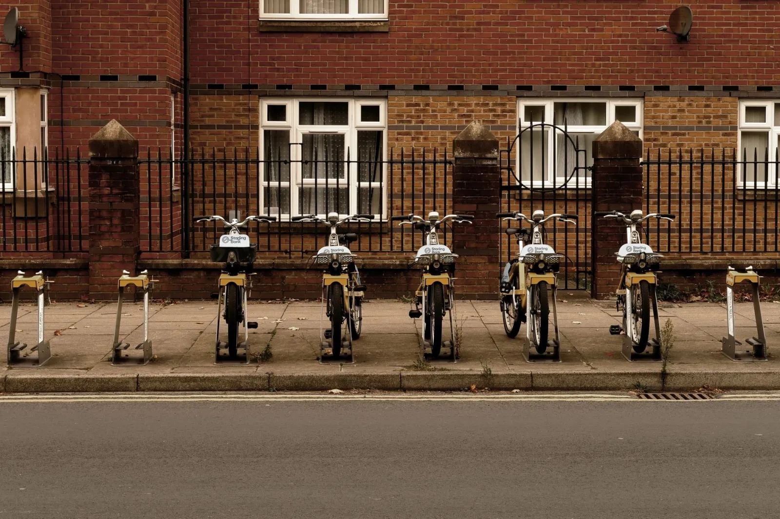 Row of bicycles parked in an urban setting against a brick building