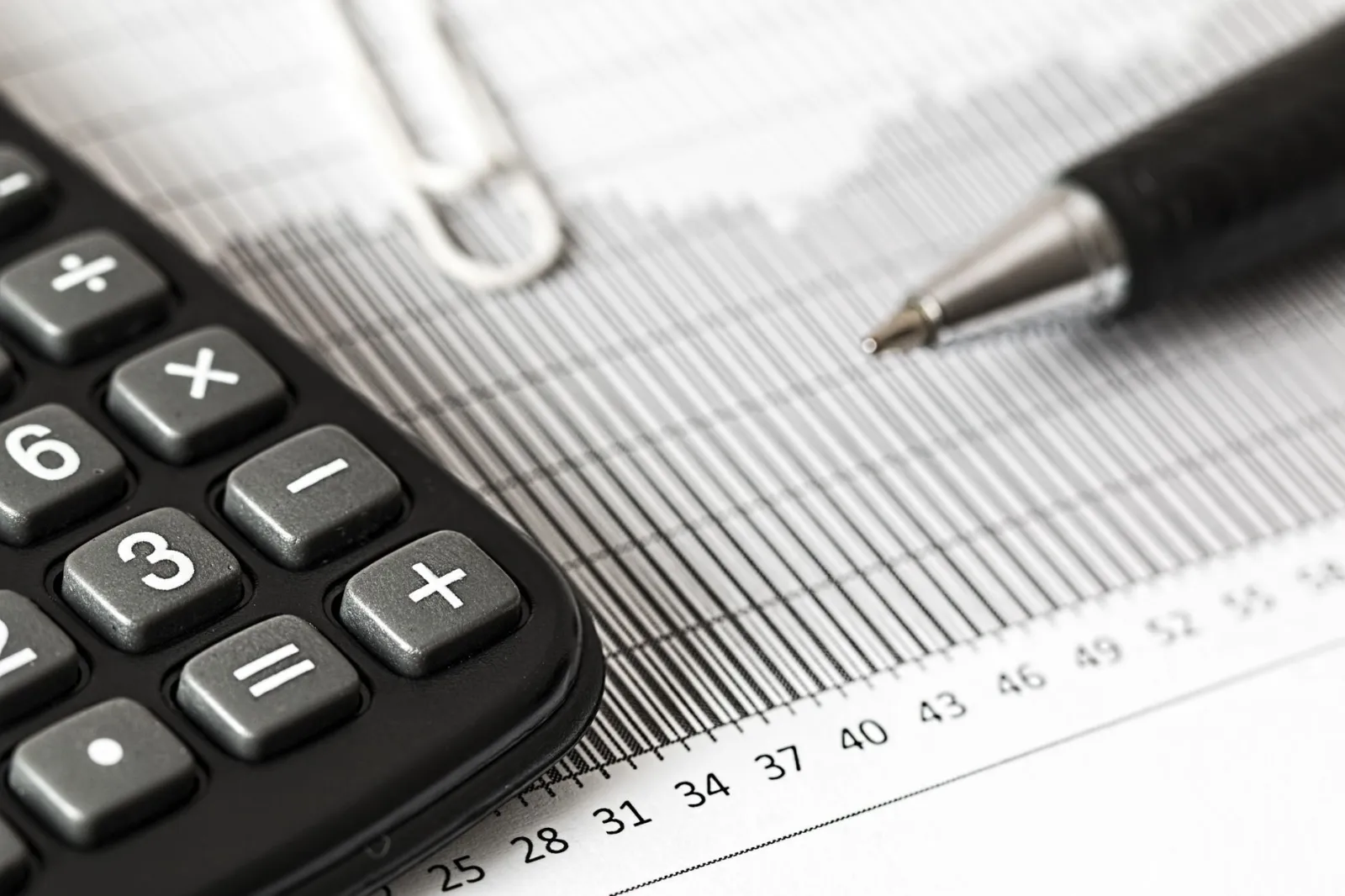 Close-up of a calculator and pen on a bar graph, representing finance and accounting.
