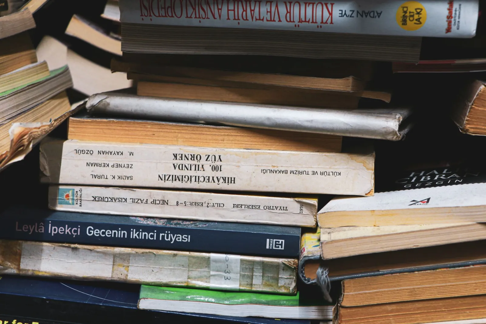 A close-up view of diverse vintage books stacked in a cozy indoor environment.
