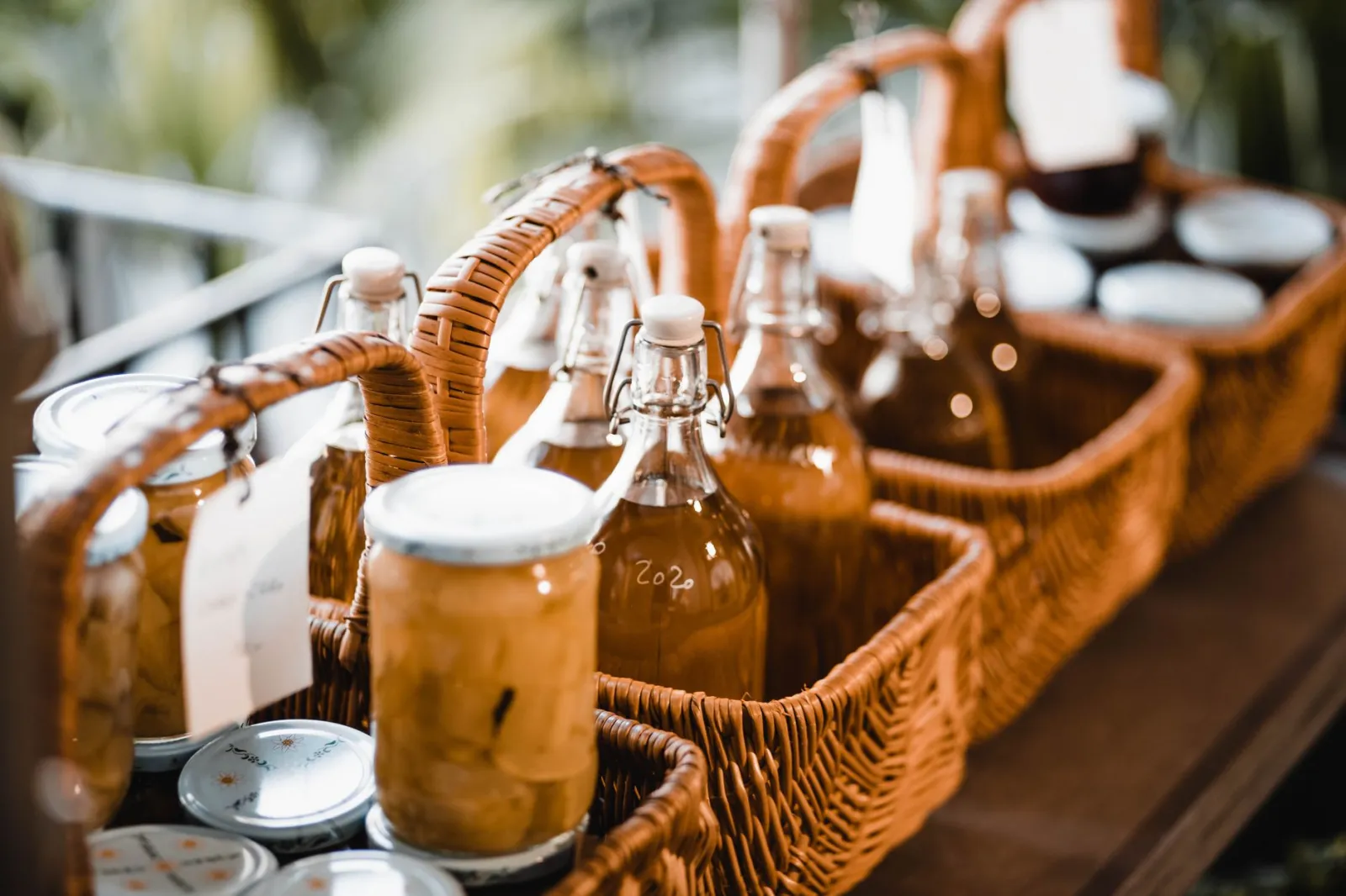 An assortment of jars and bottles in wicker baskets captured outdoors with natural light.